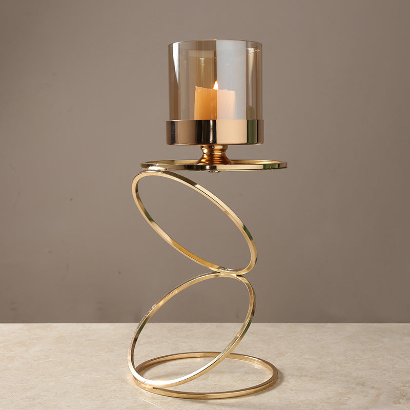 Large gold helix candle stand with glass cylinder on beige surface