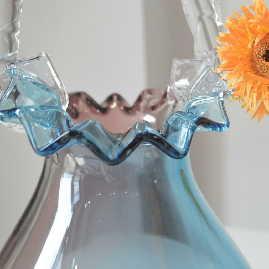 Close up detail of ruffled blue glass rim and clear textured handle