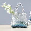 Side view of blue bubble glass handbag vase with flowers