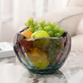 Side view of geometric glass bowl filled with grapes and fruit