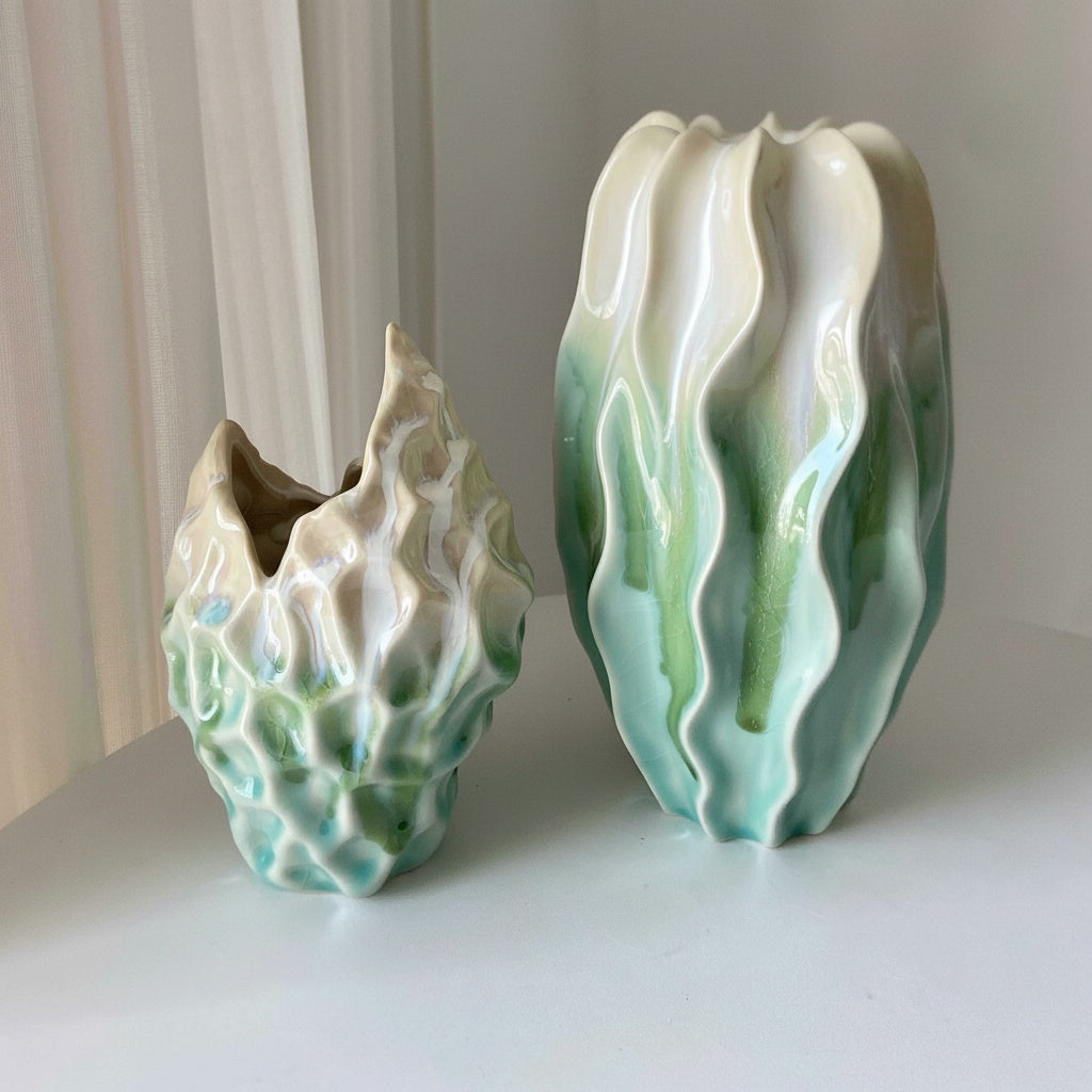 Large and medium gradient sculptural ceramic vases on a white surface