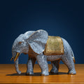Angled front view of brass elephant statue with gold saddle