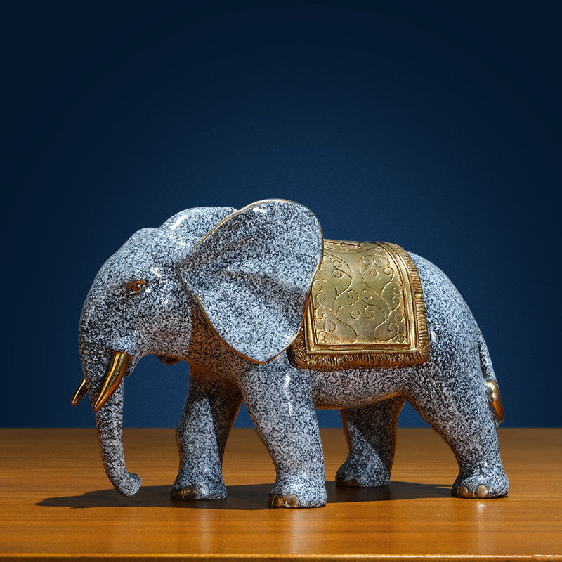 Angled front view of brass elephant statue with gold saddle
