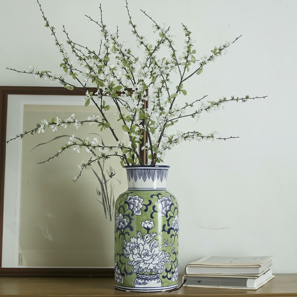 Green and blue ceramic floral vase with branches on table
