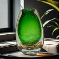 Close up of large green glass vase showing bubble details and amber base