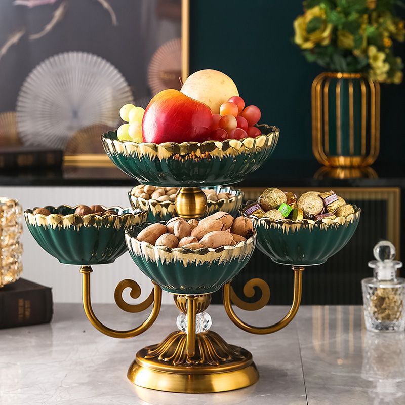 Front view of emerald green ceramic and gold tiered fruit stand filled with fruit and nuts