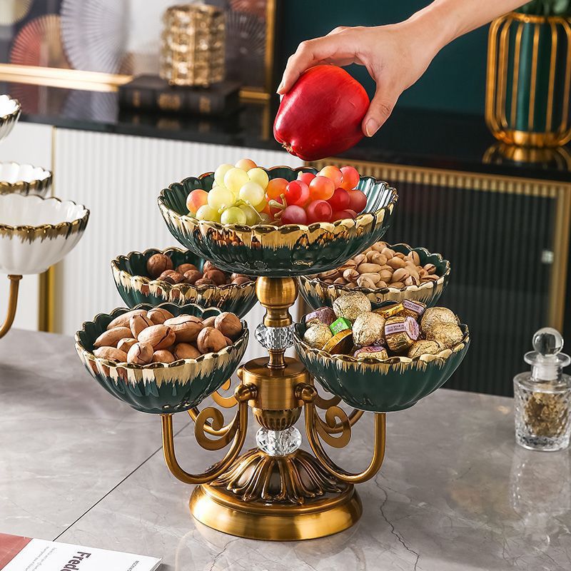 Hand placing an apple on the top bowl of the luxury green ceramic serving stand