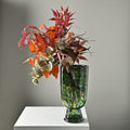 Green feathered art glass vase with autumn floral arrangement