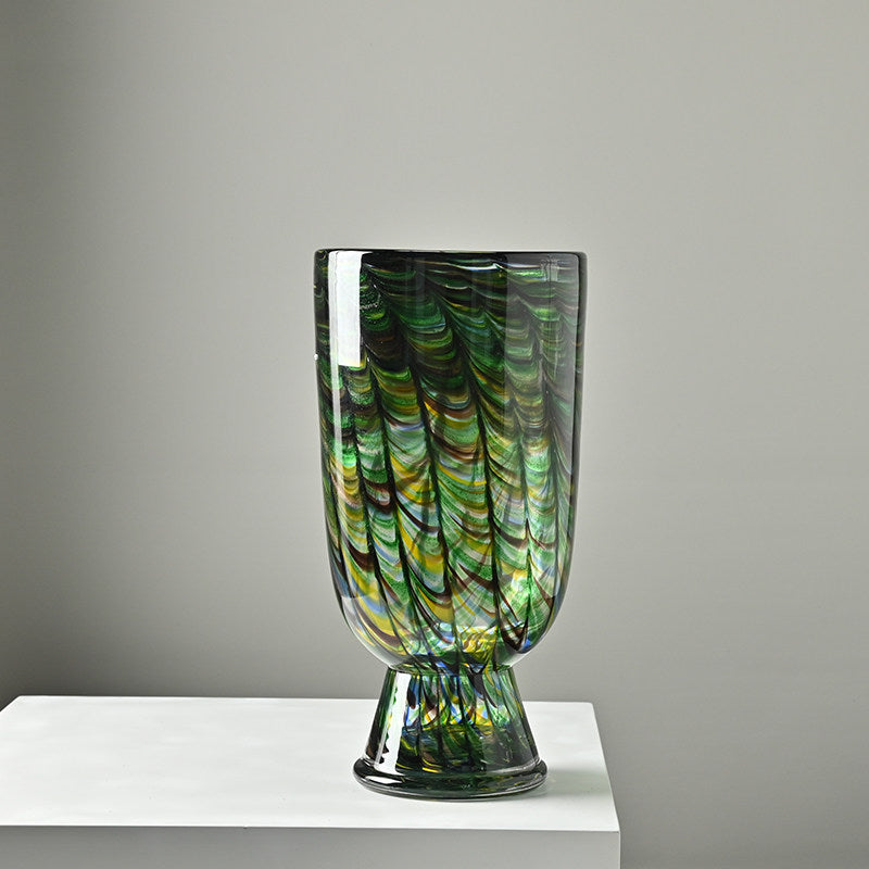 Front view of green patterned glass footed vase on white stand