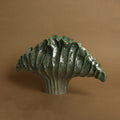 Front view of green glazed ceramic scalloped shell vase against brown background