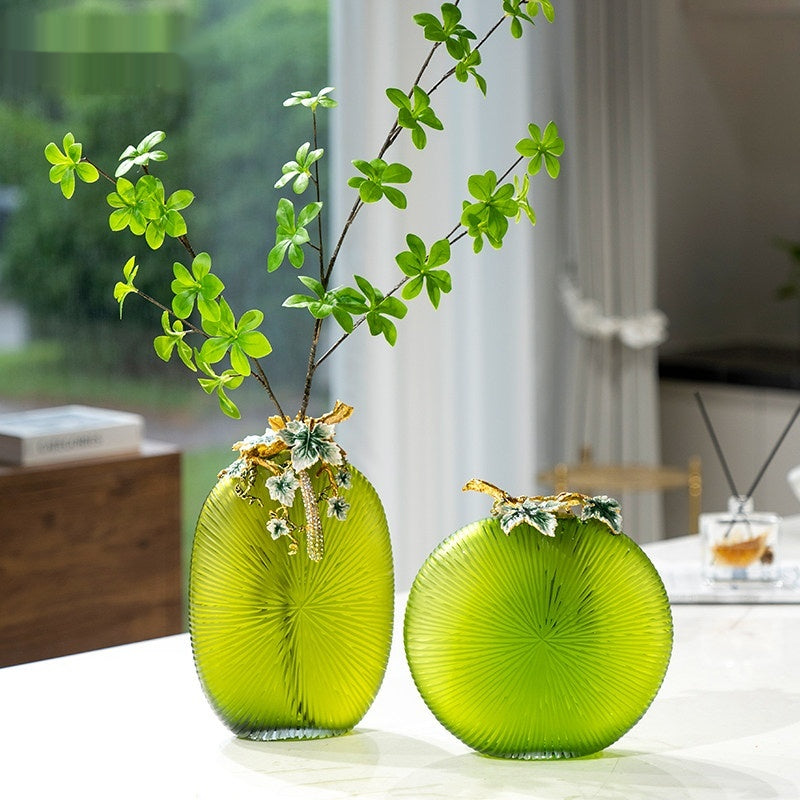 Green ribbed glass vase with enamel leaf detail on table