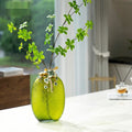 Large green radial glass vase with floral arrangement