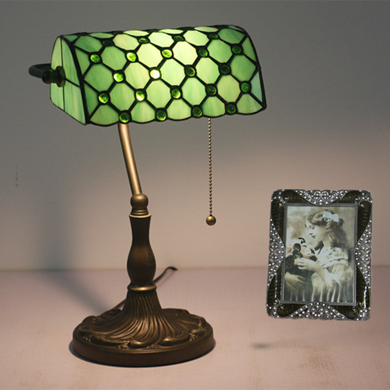 Illuminated green stained glass banker lamp on desk