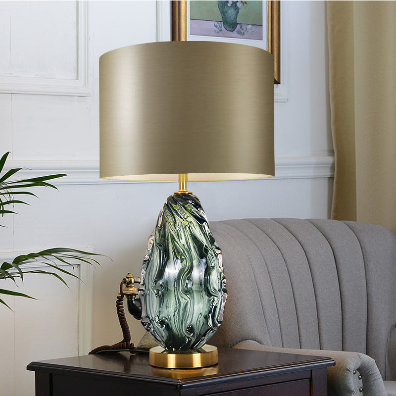 Front view of green swirled glass table lamp with gold shade lit
