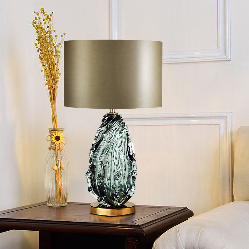 Lit green glass lamp with organic texture on wooden table