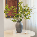 Grey ceramic vase with vertical ribbing holding green leaves