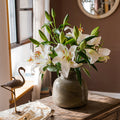 Grey speckled glass vase with white lilies on wooden table