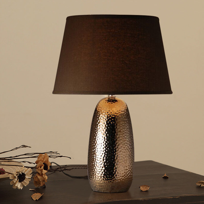Front view of hammered bronze ceramic table lamp with dark shade
