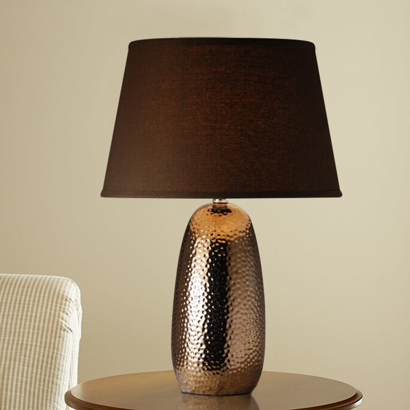 Angled view of hammered bronze lamp on wooden table