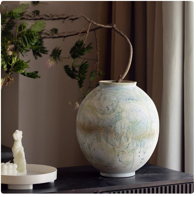 Large round ceramic vase with artistic brushstrokes on dark table