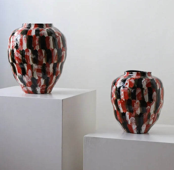 Two hand-painted ceramic vases displayed on pedestals