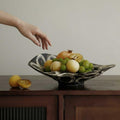 Side profile of wavy black and white ceramic bowl on wooden surface