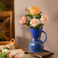 Blue pitcher vase styled with orange roses