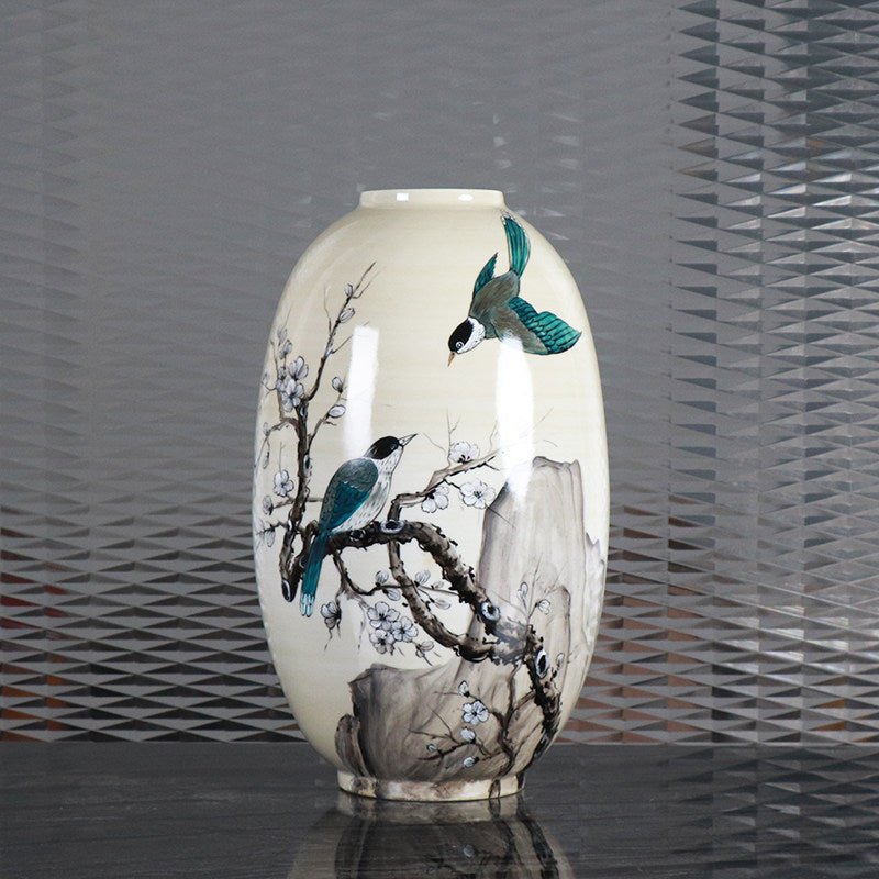 Front view of cream ceramic vase with bird and blossom art