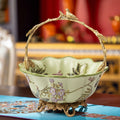 Front view of ceramic basket with brass bird handle on table