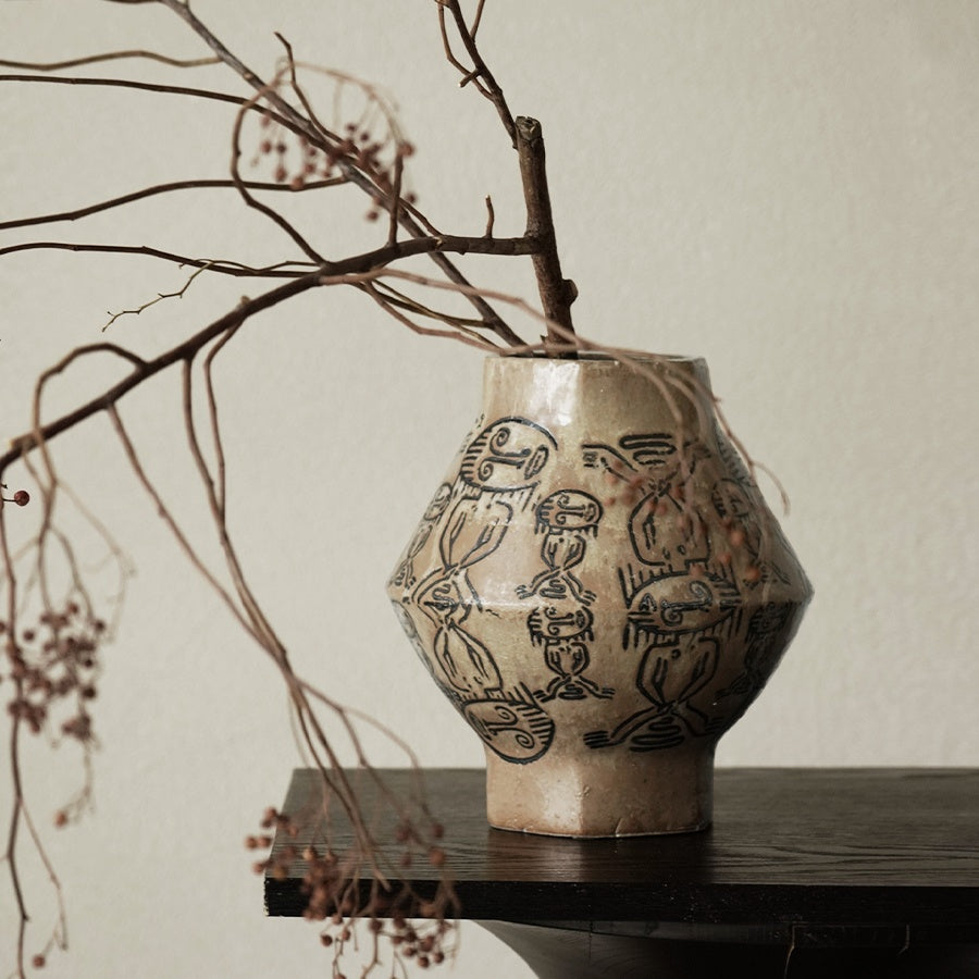 Close up of hand painted tribal motifs on ceramic vase with dried branches