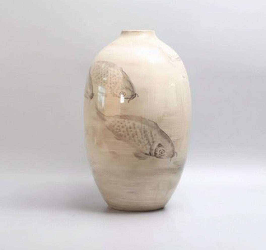 Angled view of beige ceramic vase with grey fish motif