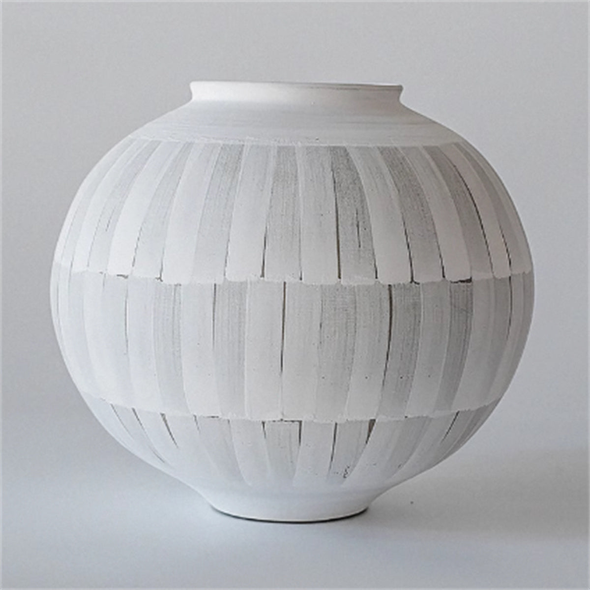 Front view of matte white and grey striped ceramic spherical vase