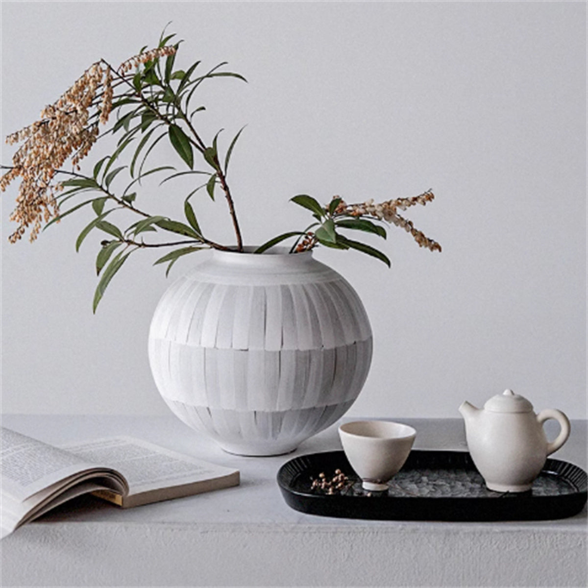 Ceramic globe vase styled with tea set and open book