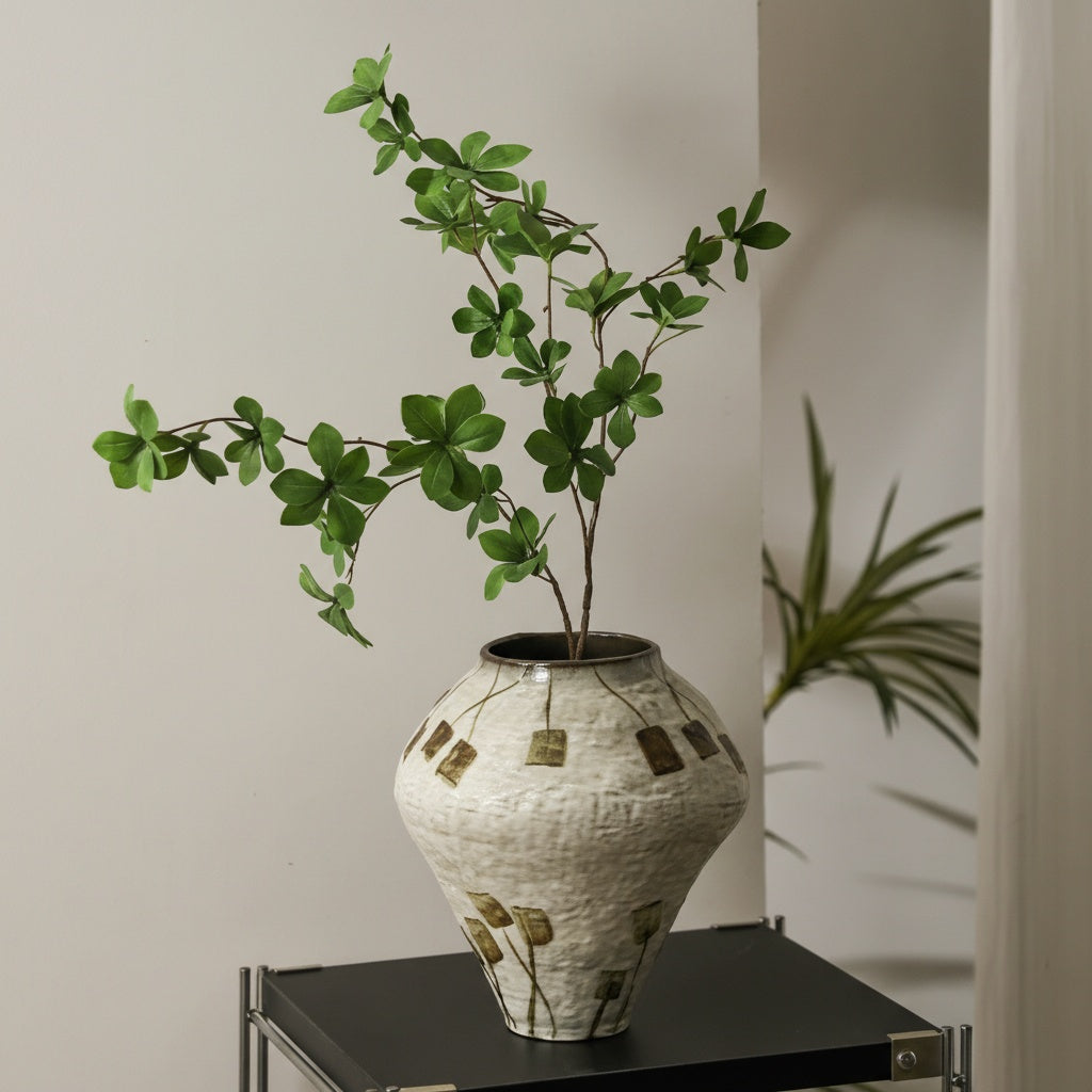 Ceramic vase styled with greenery on metal shelf