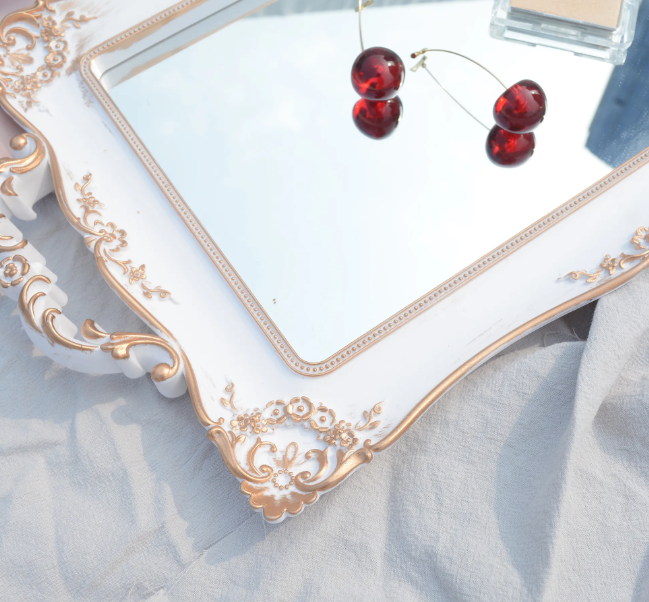 Close up detail of the intricate floral carving on the corner of the white and gold tray frame