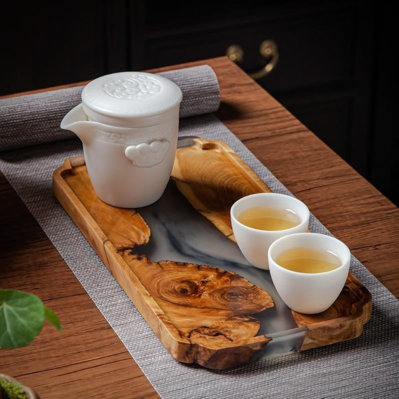 Angled view of luxury burl wood and smoky resin serving tray styled with a white porcelain tea set