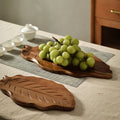 Elegant wooden leaf tray displaying fresh green grapes on a linen table runner