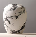 Close up of tall white ceramic vase with abstract black ink design