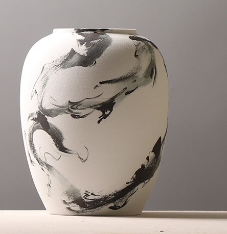 Close up of tall white ceramic vase with abstract black ink design
