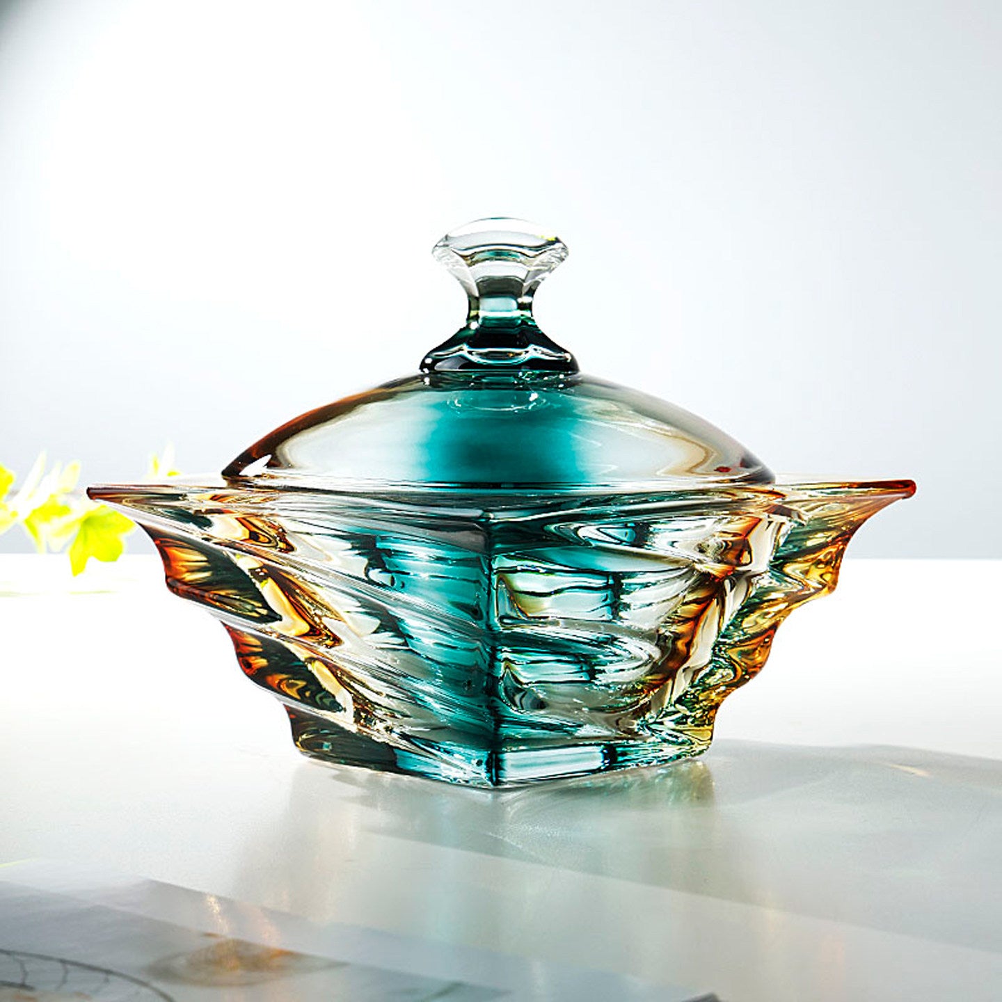 Front view of iridescent teal and amber glass jar with lid