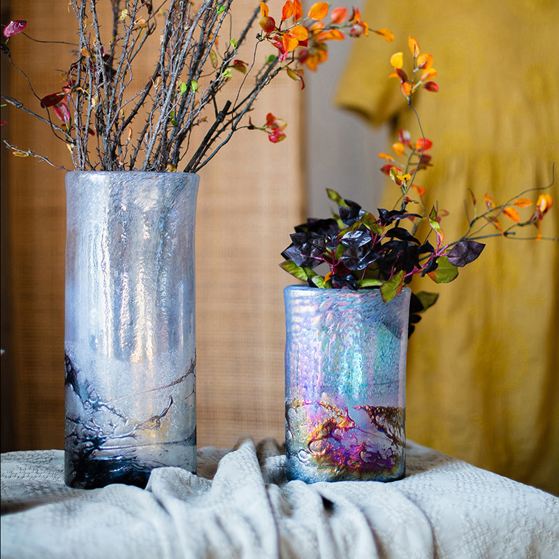 Two iridescent textured glass vases with floral arrangements on a table
