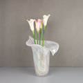 Iridescent white glass vase with lily shape holding flowers