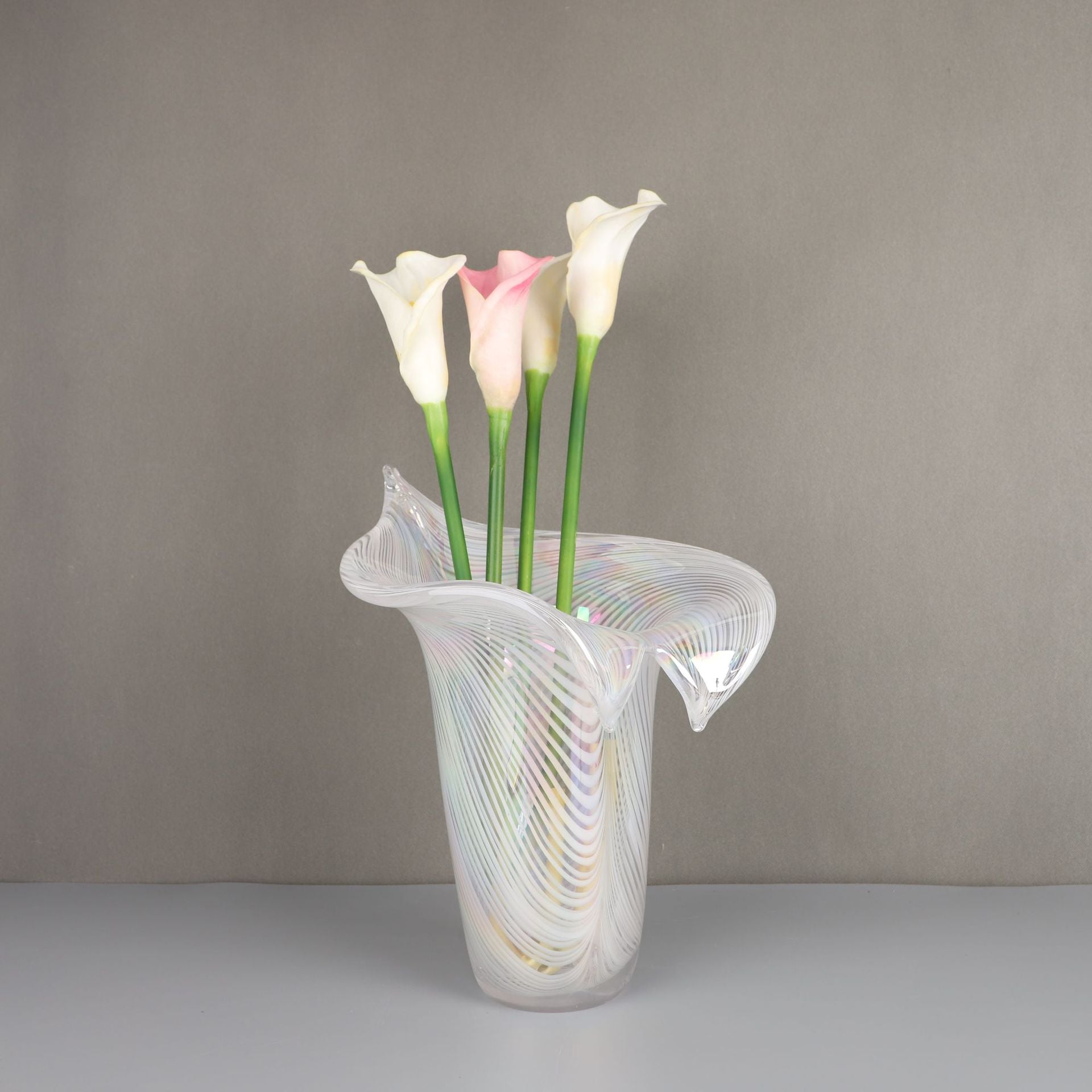 Iridescent white glass vase with lily shape holding flowers