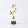 Large gold copper sculpture with four butterflies rising from a green marble base
