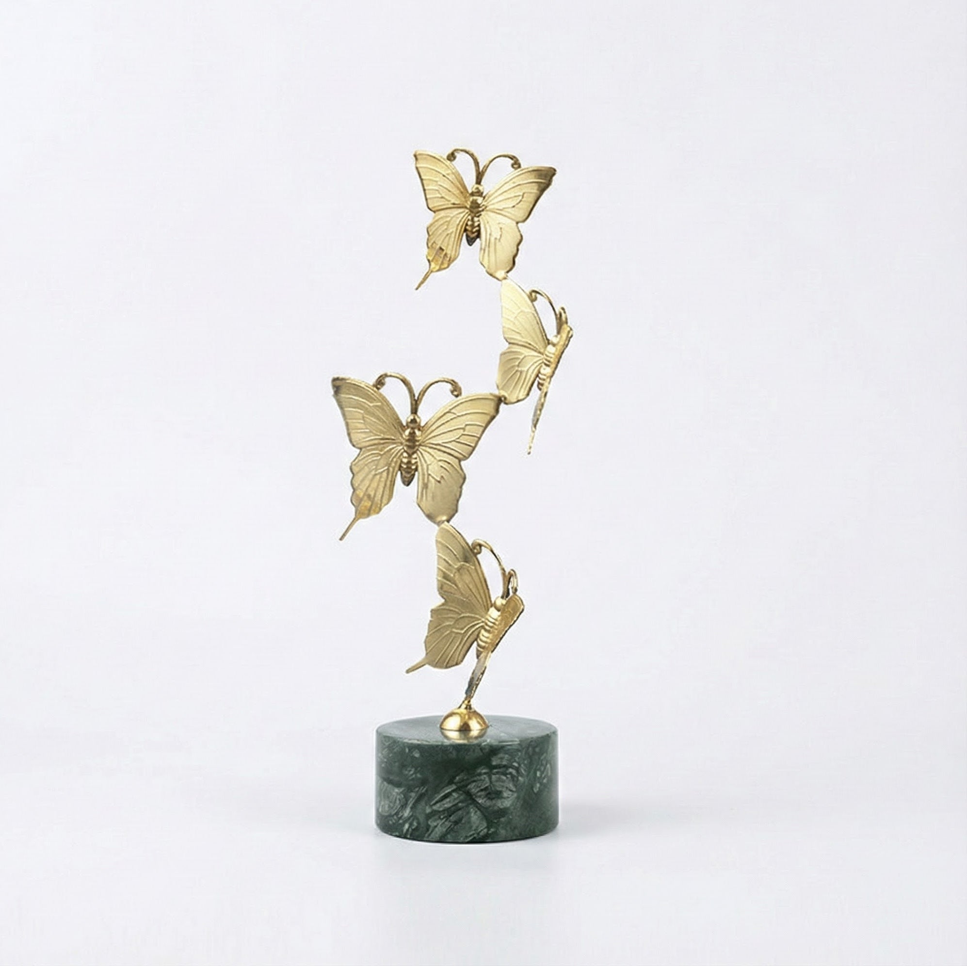 Large gold copper sculpture with four butterflies rising from a green marble base