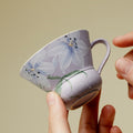 Person holding lavender floral ceramic teacup