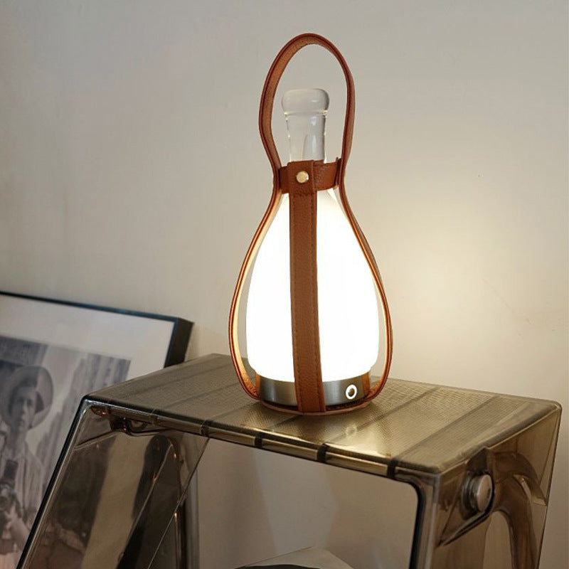 Illuminated portable lantern lamp with leather strap on shelf