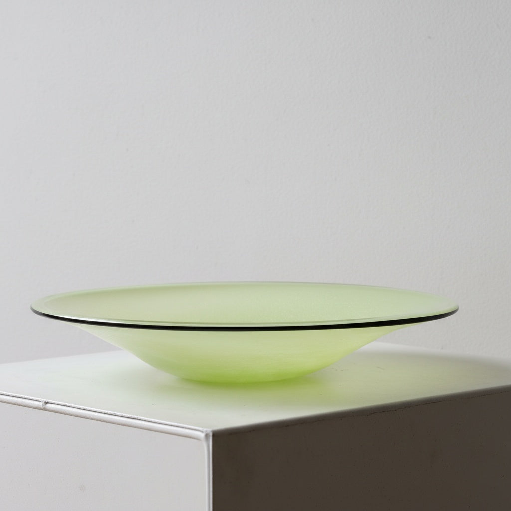 Side profile of lime green glass bowl with black rim