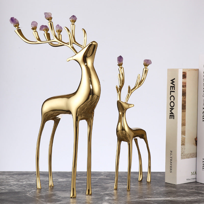 Copper elk figurines with amethyst stones attached to the antlers placed next to books