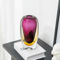 Angled view of thick art glass vase on books